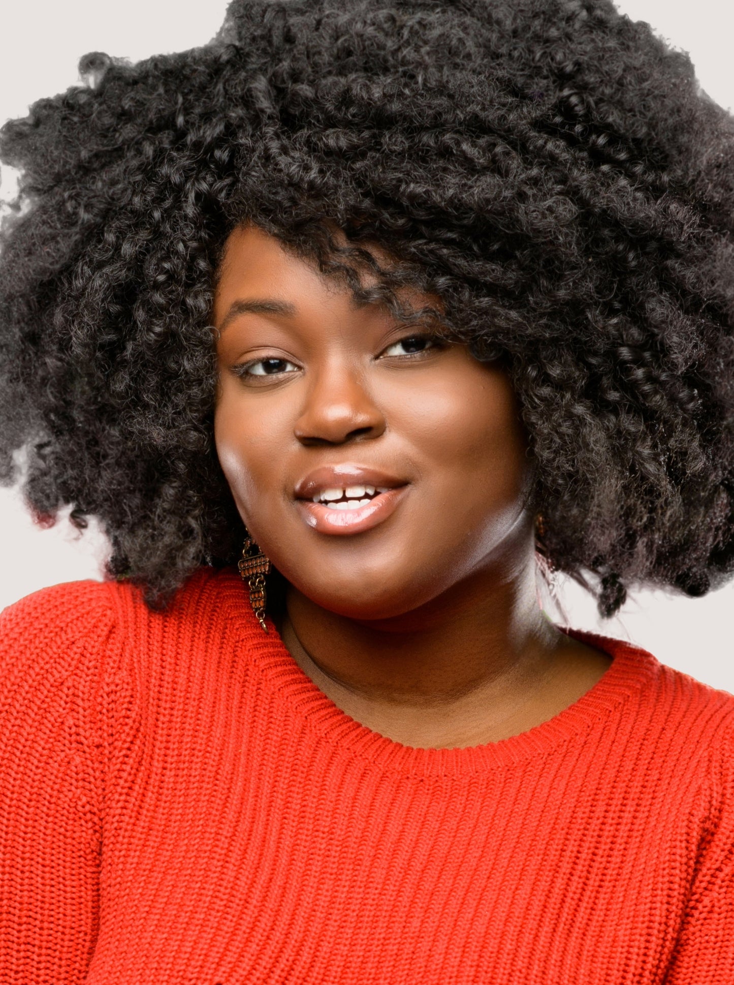 Girl smiling at the camera wearing a bright orange jumper from Plus Size Fashion brand, Adirah 